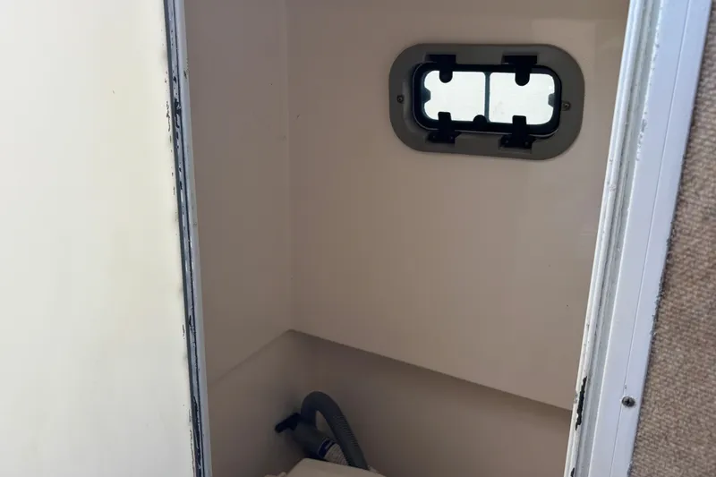 Slide: The Image of Interior of 2000 Shamrock 260 Express boat, featuring a small window and plumbing. - 16
