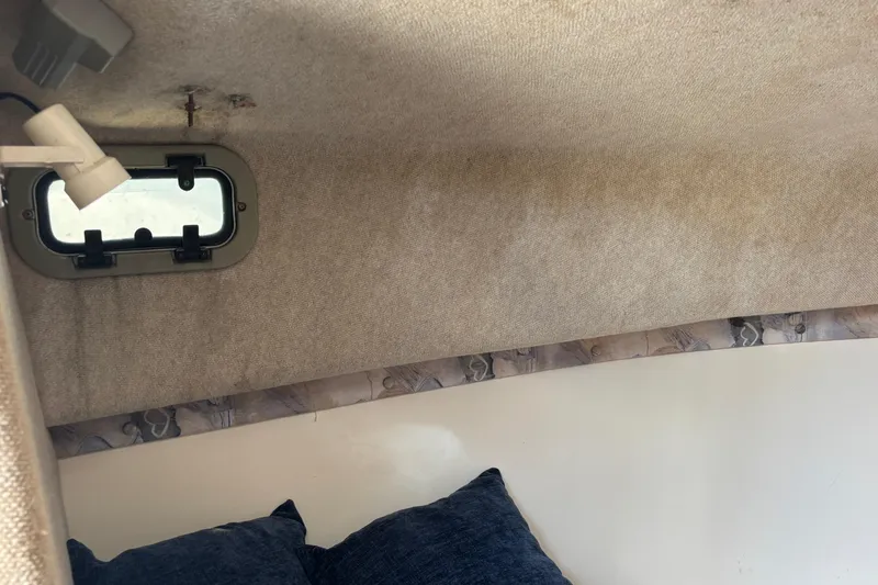 Slide: The Image of Interior cabin of 2000 Shamrock 260 Express boat with window and cushions. - 19