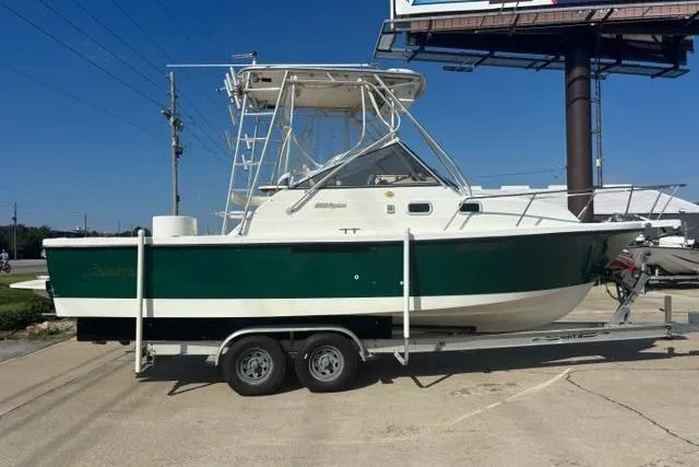 Slide: The Image of 2000 Shamrock 260 Express boat on trailer, green and white, parked outdoors. - 2