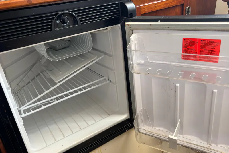 Slide: The Image of Open refrigerator in a 2000 Shamrock 260 Express boat, showing empty shelves. - 27