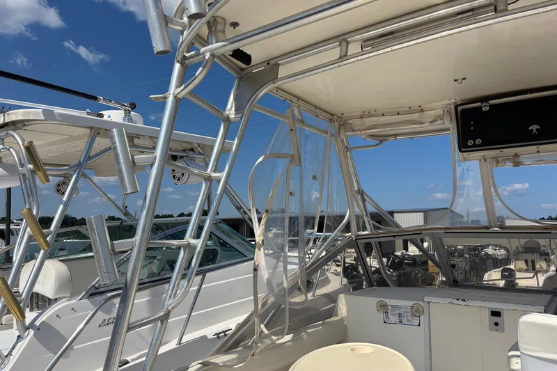 Slide: The Image of 2000 Shamrock 260 Express boat with aluminum frame and clear canopy under blue sky. - 57