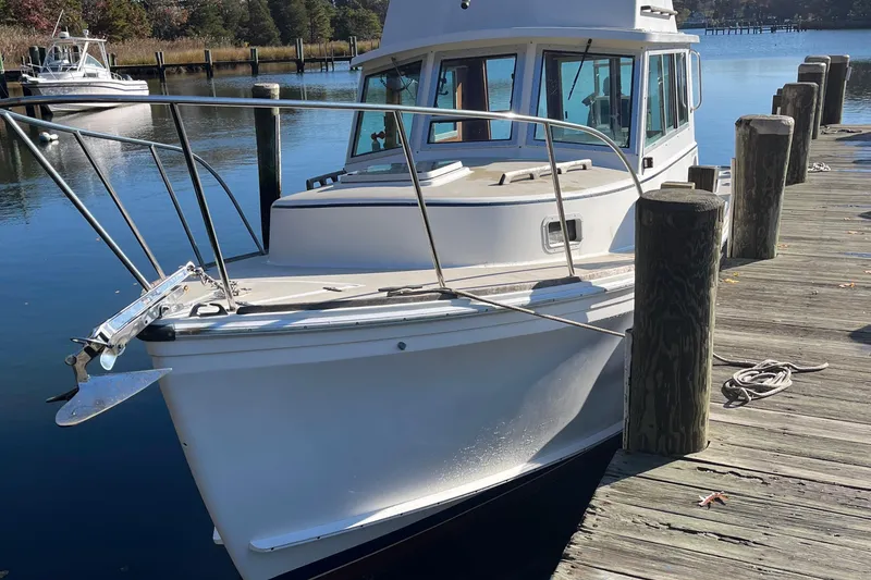 Slide: The Image of 1986 Cape Dory 28 Flybridge boat docked by wooden pier on a sunny day. - 10