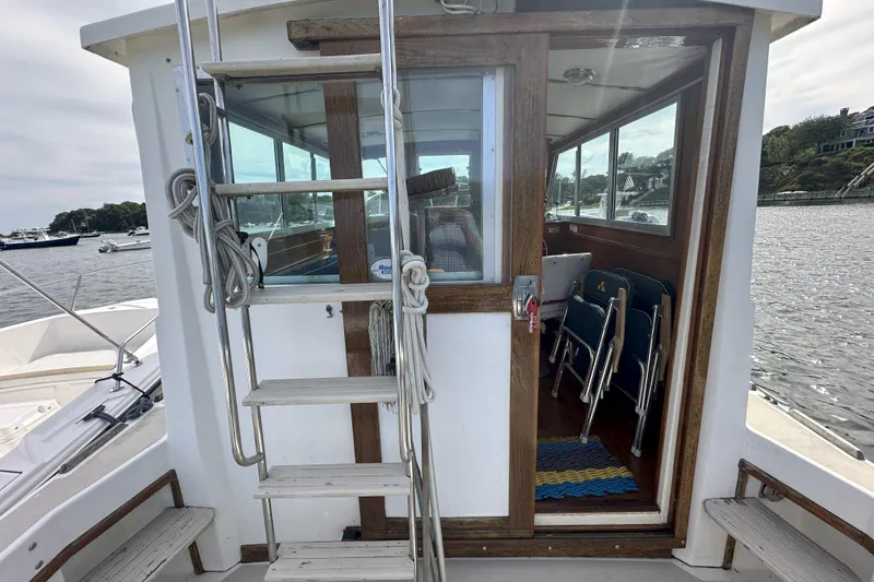 Slide: The Image of 1986 Cape Dory 28 Flybridge boat with wooden interior and exterior ladder on a calm waterway. - 2