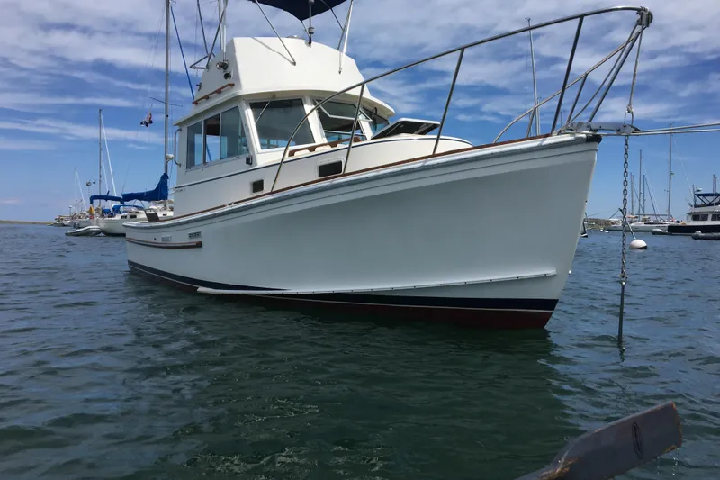 Slide: The Image of 1986 Cape Dory 28 Flybridge boat on calm water, clear sky background. - 3