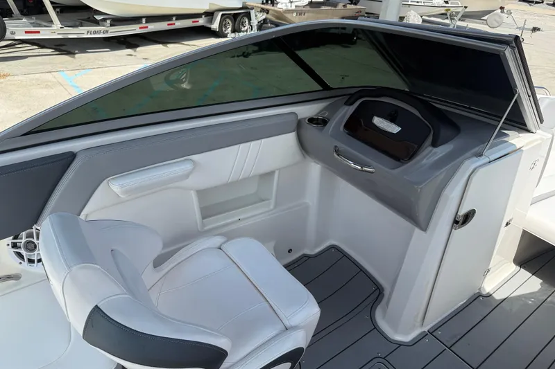 Slide: The Image of 2021 Chaparral 230 SSi boat interior with white seating and sleek dashboard design. - 10