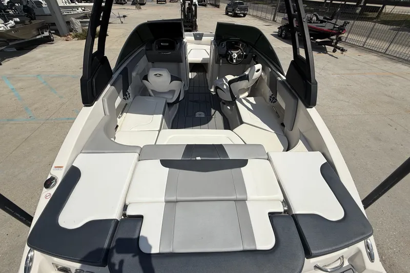 Slide: The Image of 2021 Chaparral 230 SSi boat interior with seating and steering wheel, docked outdoors. - 8