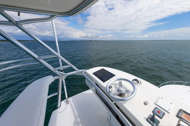 Slide: The Image of 2009 Viking 74 Enclosed Bridge yacht helm overlooking open sea and cloudy sky. - 102
