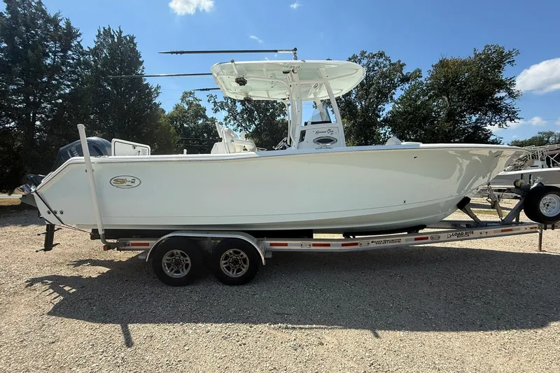The Image of 2015 Sea Hunt Gamefish 27 boat on trailer, parked outdoors under clear sky. - 1