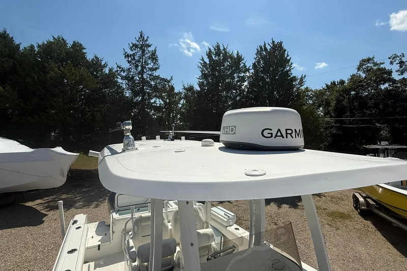 Slide: The Image of 2015 Sea Hunt Gamefish 27 boat with Garmin radar on top, surrounded by trees. - 20