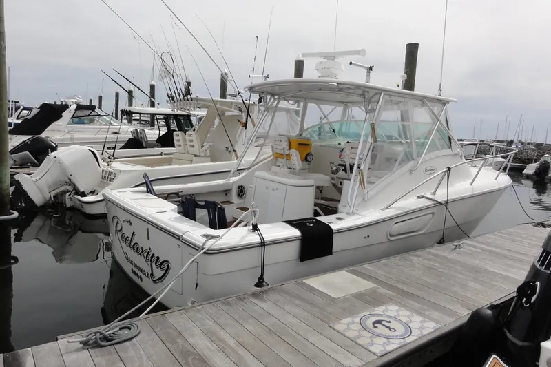 The Image of 2002 Rampage 30 Open boat docked at marina, featuring fishing rods and spacious deck. - 0