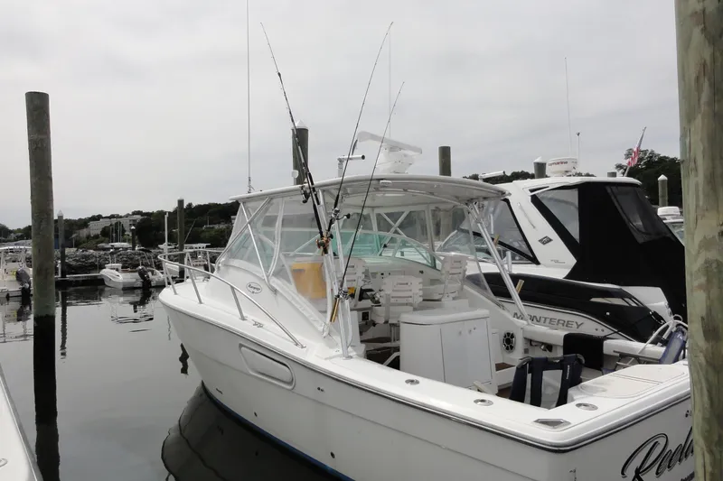 Slide: The Image of 2002 Rampage 30 Open boat docked at marina, featuring fishing rods and spacious cockpit. - 5