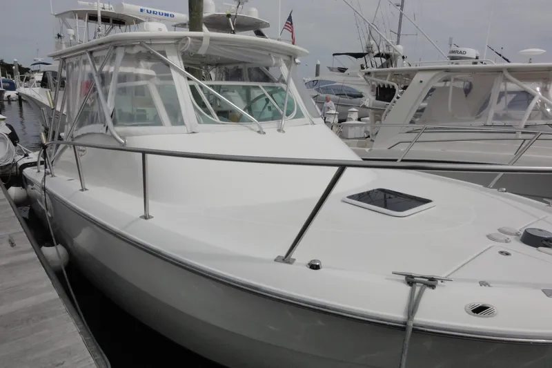 Slide: The Image of 2002 Rampage 30 Open boat docked at marina, featuring sleek white design. - 9