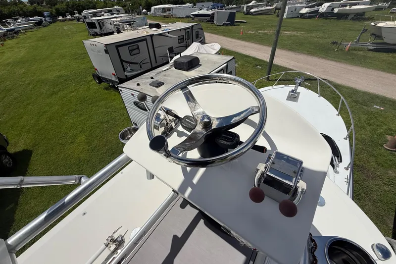 Slide: The Image of 1981 T Craft Gulfstream 30 boat helm with steering wheel and controls, parked near RVs. - 23