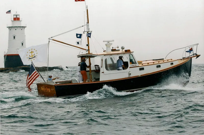 Slide: The Image of 1994 John Williams Stanley 36 boat sailing near a lighthouse with flags flying. - 1