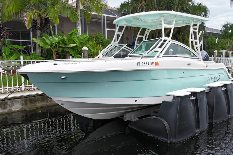 Slide: The Image of 2019 Robalo R247 Dual Console boat docked, featuring sleek design and light blue hull. - 2