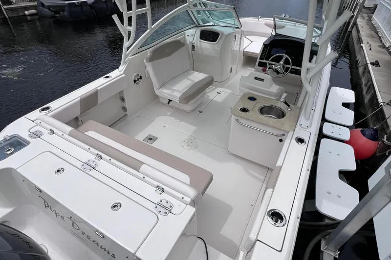 Slide: The Image of 2019 Robalo R247 Dual Console boat interior with seating and helm, docked by water. - 24