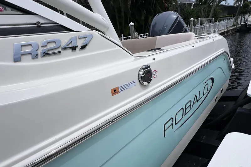Slide: The Image of 2019 Robalo R247 Dual Console boat docked, showcasing sleek design and branding. - 26