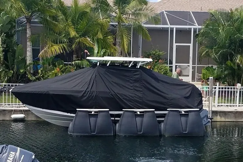 Slide: The Image of 2019 Robalo R247 Dual Console boat covered, docked near tropical plants. - 4