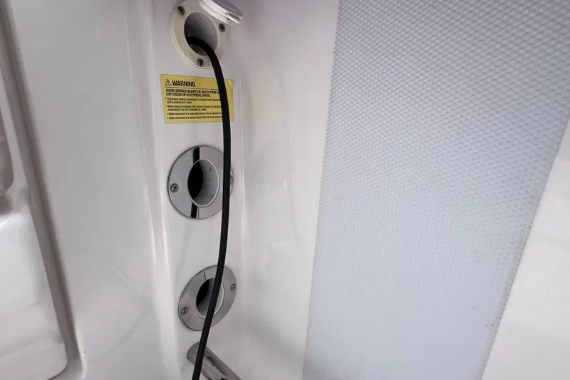 Slide: The Image of 2019 Robalo R247 Dual Console boat interior with warning label and cable ports. - 49