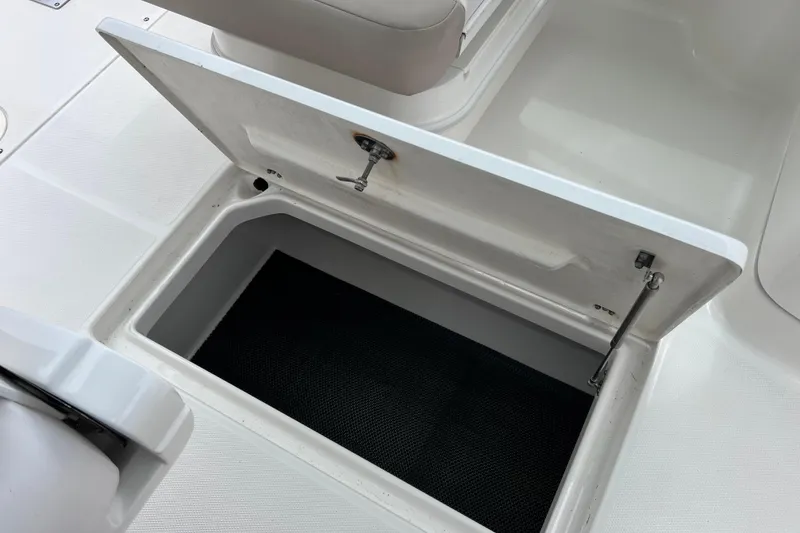 Slide: The Image of 2019 Robalo R247 Dual Console storage compartment with open lid, showcasing interior space. - 54