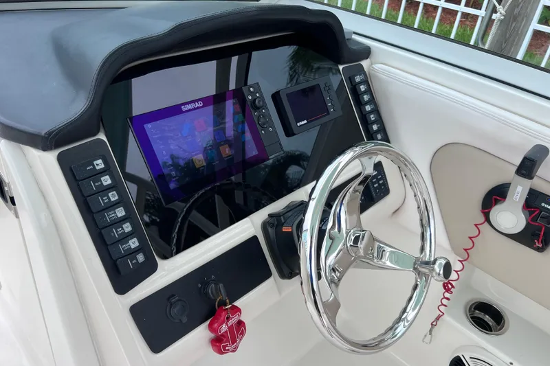 Slide: The Image of 2019 Robalo R247 Dual Console boat dashboard with Simrad display and chrome steering wheel. - 56