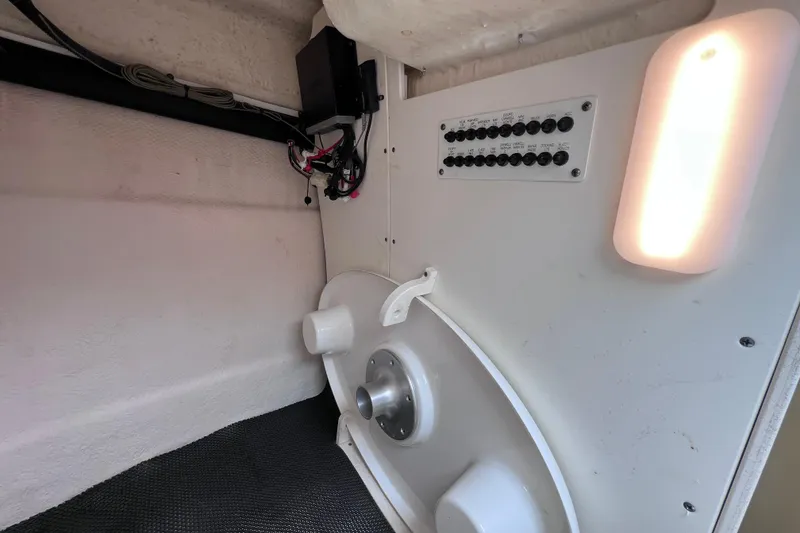 Slide: The Image of Interior view of a 2019 Robalo R247 Dual Console boat, featuring electrical panel and lighting. - 62