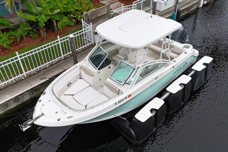 Slide: The Image of 2019 Robalo R247 Dual Console boat docked in a canal, surrounded by lush greenery. - 7