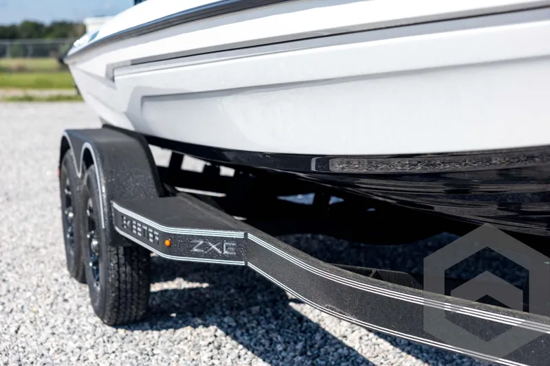 Slide: The Image of 2026 Skeeter ZXE21 boat trailer on gravel, showcasing sleek design and dual wheels. - 12