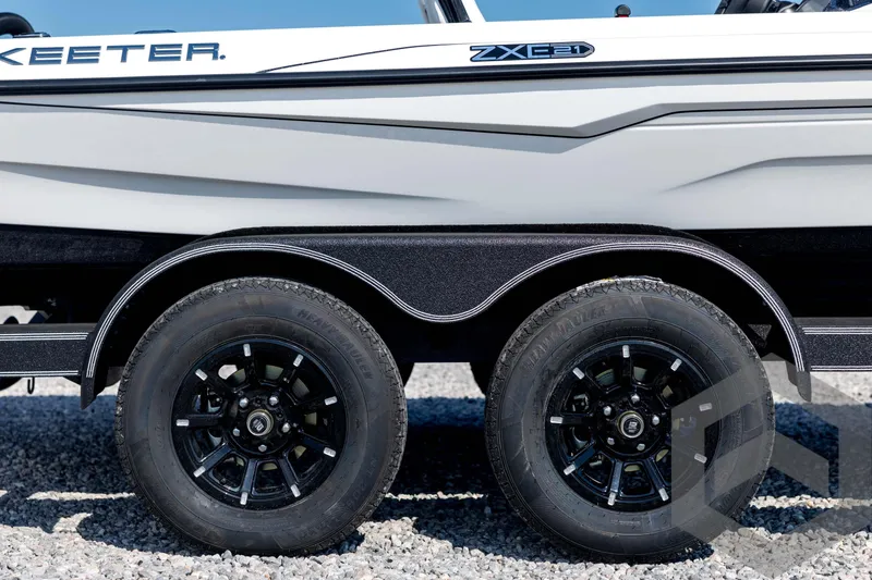 Slide: The Image of 2026 Skeeter ZXE21 boat trailer with dual black wheels on gravel surface. - 14