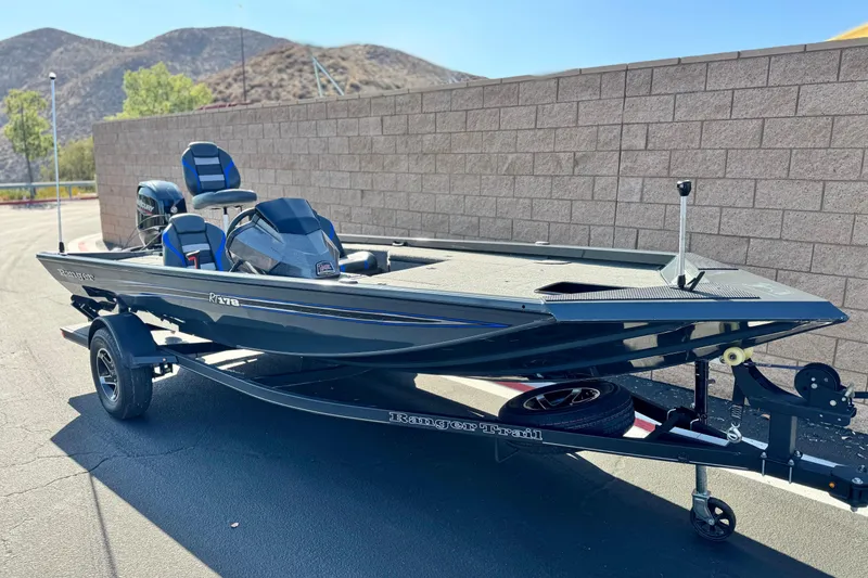 Slide: The Image of 2021 Ranger RT178 boat on trailer, parked near a stone wall with hills in the background. - 1