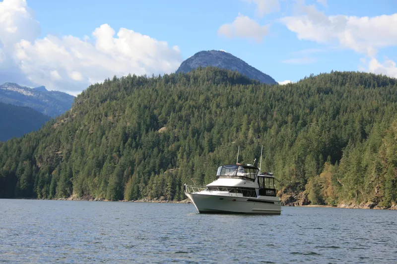 Slide: The Image of 1989 Ocean Alexander 420 Cockpit Motor Yacht on scenic lake with forested mountains. - 49