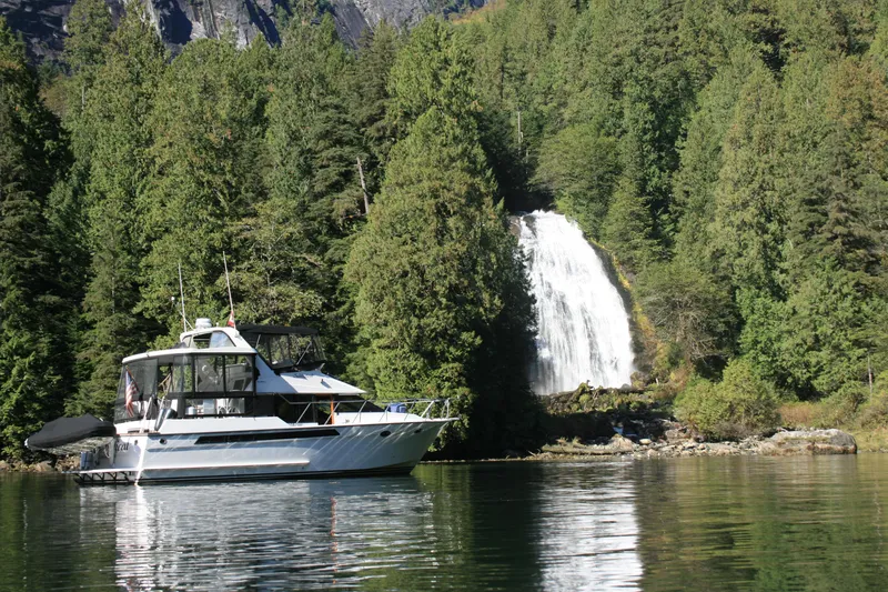 Slide: The Image of 1989 Ocean Alexander 420 Cockpit Motor Yacht near a scenic waterfall and lush forest. - 0
