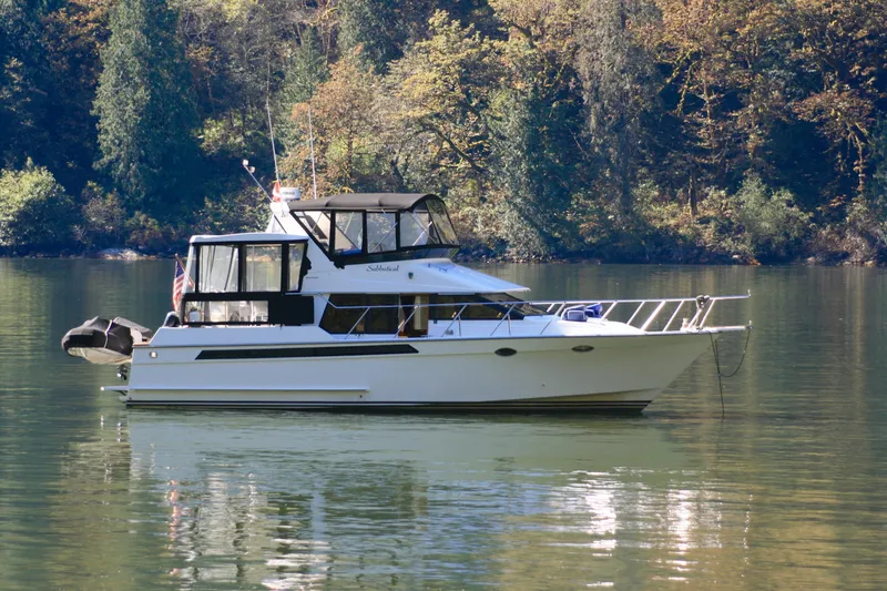 Slide: The Image of 1989 Ocean Alexander 420 Cockpit Motor Yacht on tranquil water, surrounded by trees. - 1