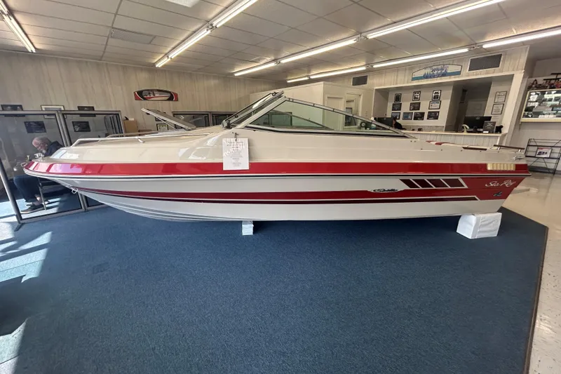 The Image of 1987 Sea Ray 19 Seville Cuddy Cabin boat displayed indoors, featuring red and white design. - 0