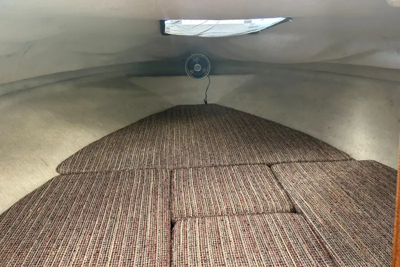 Slide: The Image of 1987 Sea Ray 19 Seville Cuddy Cabin interior with cushioned sleeping area and small fan. - 9