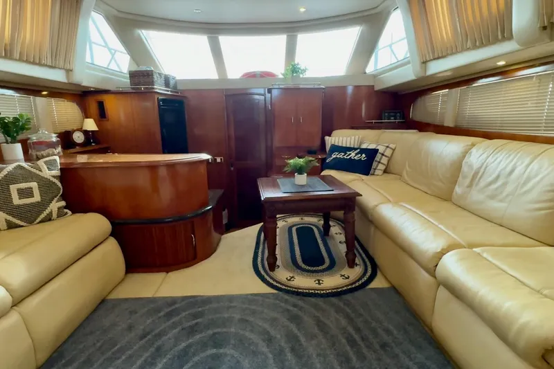 Slide: The Image of 2003 Carver 396 Motor Yacht interior with beige sofa, TV, and wooden cabinetry. - 28