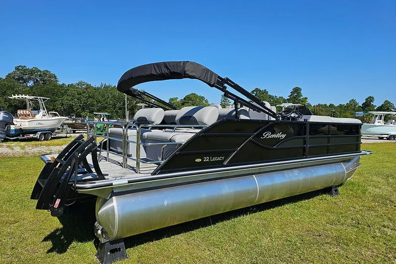 Slide: The Image of 2026 Bentley Pontoons Legacy 223 Quad Swing Back 3/4 Tritoon on grassy field. - 3