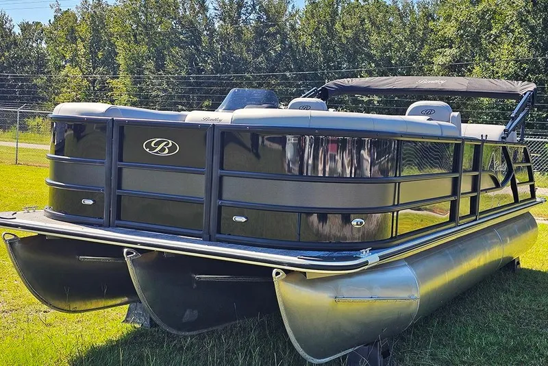 Slide: The Image of 2026 Bentley Pontoons Legacy 223 Quad Swing Back 3/4 Tritoon on grass, showcasing sleek design. - 5