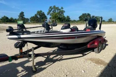 Slide: The Image of 2012 Skeeter FX20 bass boat on trailer, parked outdoors under clear blue sky. - 2