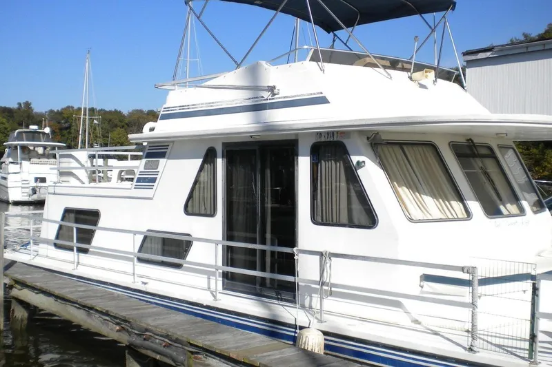 Slide: The Image of 1996 Gibson 41 Classic Houseboat docked, featuring white exterior and blue accents. - 2