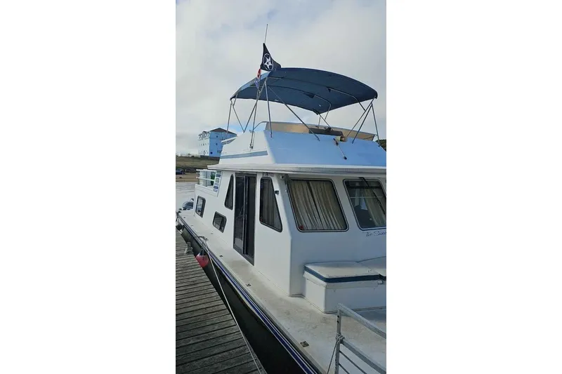 Slide: The Image of 1996 Gibson 41 Classic Houseboat docked with blue canopy and pirate flag. - 3
