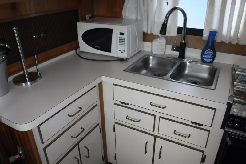 Slide: The Image of 1994 Gibson 41 Classic Houseboat kitchen with microwave, double sink, and white cabinetry. - 69