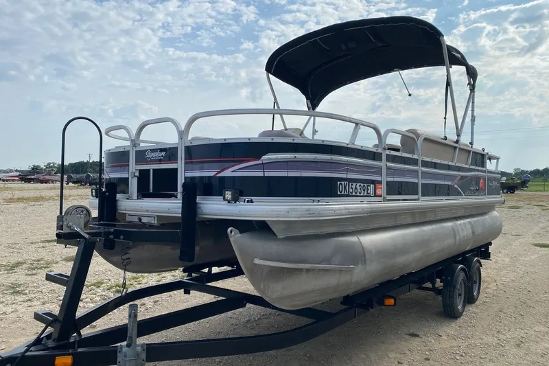 Slide: The Image of 2015 Sun Tracker Fishin' Barge 20 DLX pontoon boat on trailer, parked outdoors. - 2