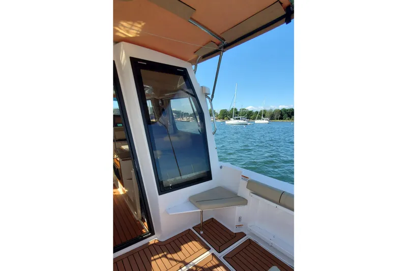 Slide: The Image of 2024 Ranger Tugs R-27 boat interior with seating, overlooking a serene water view. - 10