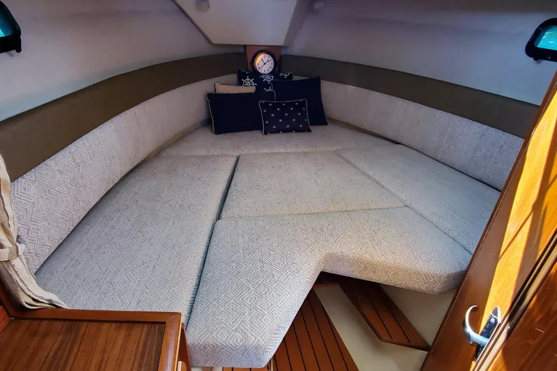 Slide: The Image of 2024 Ranger Tugs R-27 cabin interior with cozy bedding and nautical decor. - 24