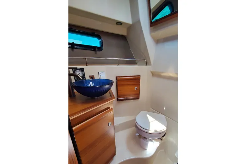Slide: The Image of 2024 Ranger Tugs R-27 bathroom with modern sink and toilet, featuring wood cabinetry. - 25