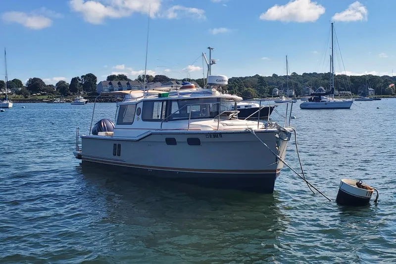 Slide: The Image of 2024 Ranger Tugs R-27 boat moored in a scenic harbor with sailboats. - 4
