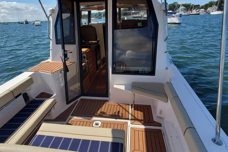 Slide: The Image of 2024 Ranger Tugs R-27 boat interior with seating, open door, and scenic water view. - 7