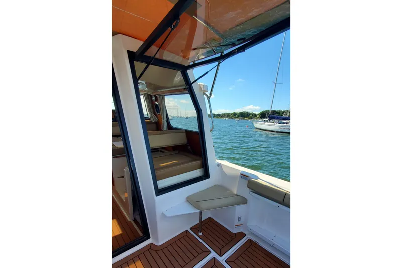 Slide: The Image of 2024 Ranger Tugs R-27 interior with open window, overlooking serene waters and sailboats. - 9