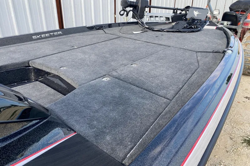 Slide: The Image of 2026 Skeeter ZXE21 boat deck with carpeted surface and fishing equipment. - 11